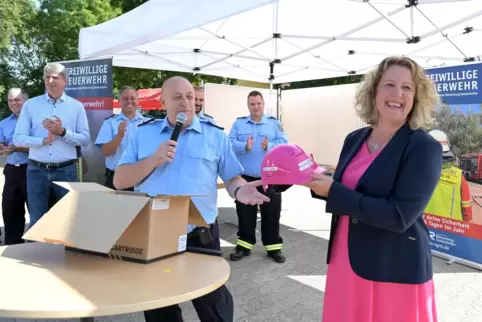 Zum Schmunzeln: Silke Schmitt-Makdice nimmt den pinkfarbenen Bauhelm von Wehrleiter Stefan Zöller entgegen. 