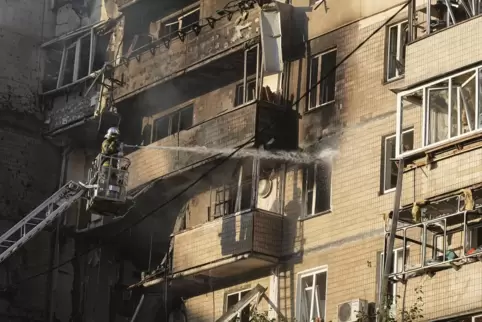 Rettungskräfte arbeiten daran, ein Feuer nach einem russischen Angriff auf ein Wohnhaus in Kiew zu löschen. 