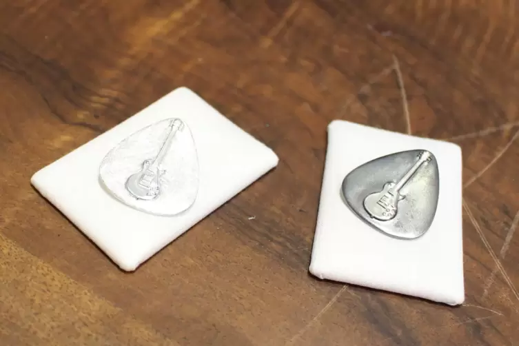 Zur Kollektion z&auml;hlen unter anderem auch silberne Anh&auml;nger in Form eines Plektrums mit einer stilisierten E-Gitarre.
