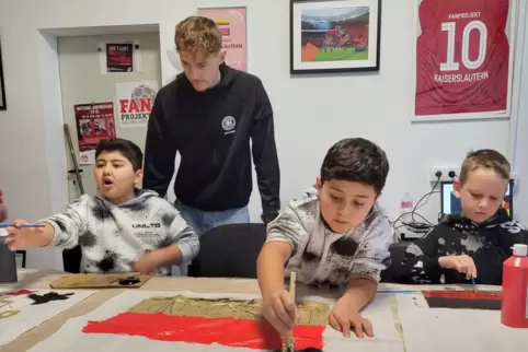 Noah Horlebein vom DFB-Fanclub gibt Tipps zur Gestaltung der Fahnen. Ehsan, Erfan und Maxim sind mit Eifer dabei.