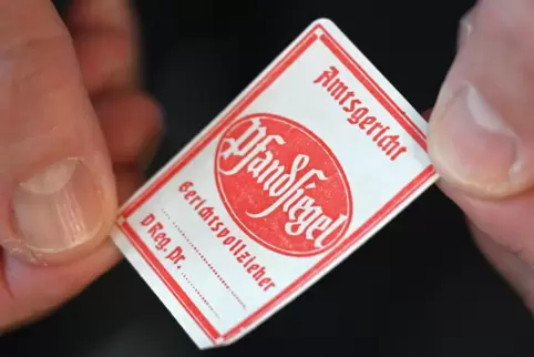 Wenn der „Kuckuck“ ruft: Ein Gerichtsvollzieher präsentiert das klassische Pfandsiegel. Wie gefährlich Vollstreckungen werden kö