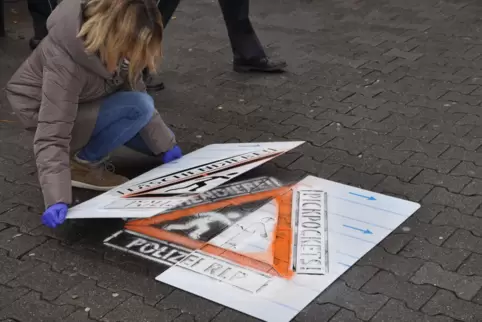 Mit Schablonen und Spezialkreide bringen Berater der Polizei Warnhinweise auf den Boden auf.