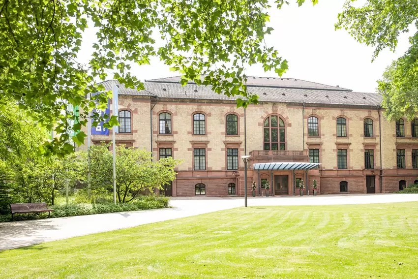 Eine Grünanlage umgibt die Zufahrt zum Gesellschaftshaus.