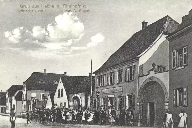 Die Ansichtskarte, datiert 25. Februar 1915, zeigt einen Teil der Heßheimer Hauptstraße mit der Gaststätte Zur Lokalbahn. Die fo