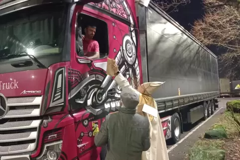 Nikolaus (Diakon Martin Pletsch) und Pfarrer Pater Pious Oroplackal überreichen einem Lkw-Fahrer auf dem Autohof Ramstein eine G