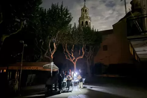 In einer Kleinstadt bei Barcelona: Gäste sitzen bei einem Stromausfall in einem Straßencafé und trinken im Licht von Taschenlamp
