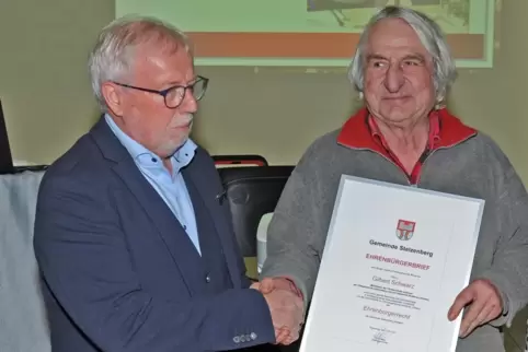 Ortsbürgermeister Fritz Geib (links) überreichte beim Stelzenberger Neujahrsempfang Gilbert Schwartz aus Breitenau im Elsass die