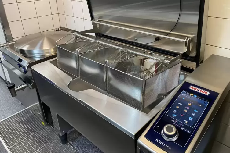 Multifunktionspfanne mit mehreren Tiegeln, dahinter gro&szlig;er neuer Kessel. 