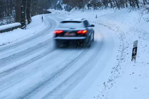 Ein Auto fährt über eine schneebedeckte Landstraße im Südharz. 