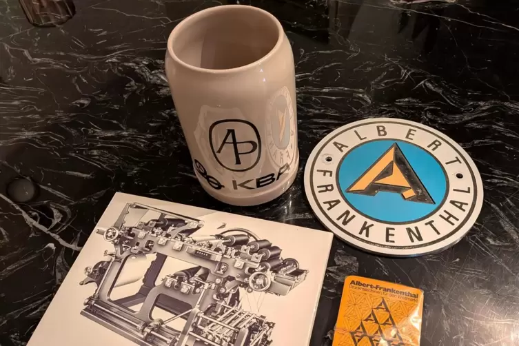 Ein KBA-Bierkrug, eine Firmenplakette, eine Kachel mit Abbildung der ersten Zeitungsrotationsmaschine sowie ein Kartenspiel.