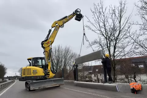 Bauarbeiter setzen Betonsockel zwischen die Stahlträger, auf die dann später die neuen Lärmschutzelemente kommen. 