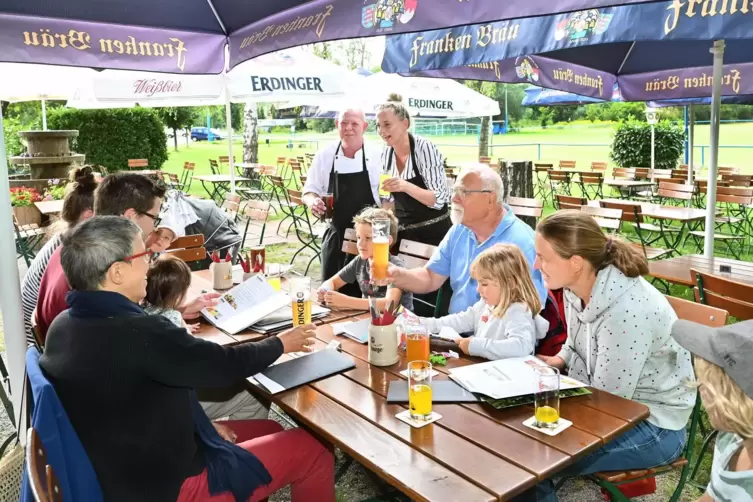 Bewirten ihre G&auml;ste im Biergarten: Aneta und Axel Lutz (stehend), Inhaber der &bdquo;Gastst&auml;tte Am Altrhein&ldquo; beim FV Heiligenstein. 