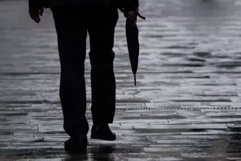 Ein Passant geht mit Regenschirm in der Hand durch Mainz