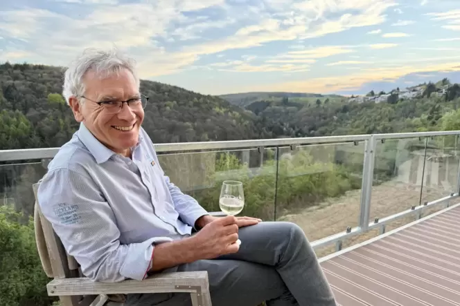 Auf dem Balkon an einem neuen Gästezimmer läutet Hausherr Julian Schraut den Feierabend ein.
