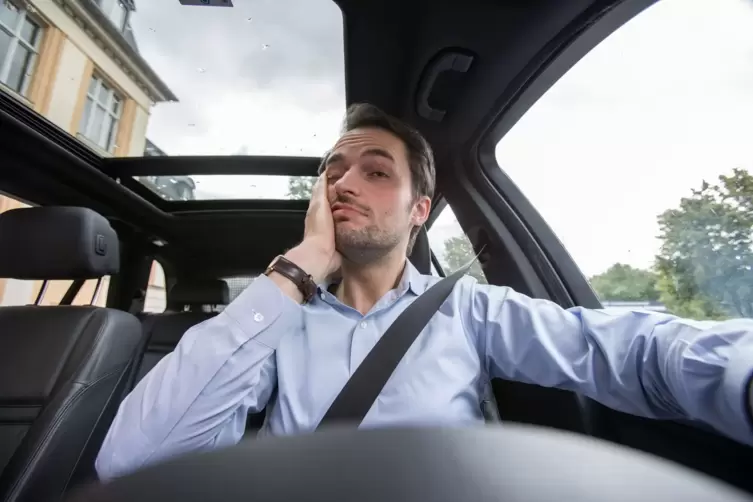 Ein Mann am Steuer fasst sich ins Gesicht