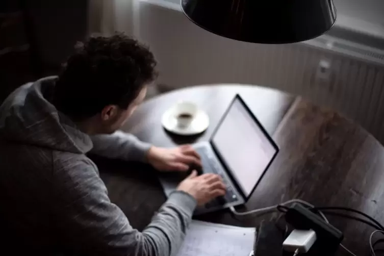 Ein Mann sitzt mit Laptop am Küchentisch
