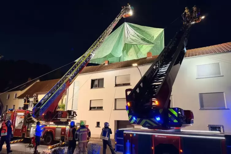 Die Feuerwehrleute sichern das Dach provisorisch.