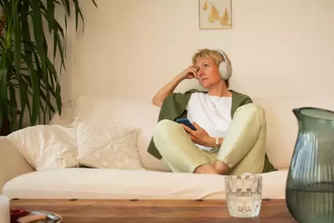 Eine Frau sitzt nachdenklich auf einem Sofa