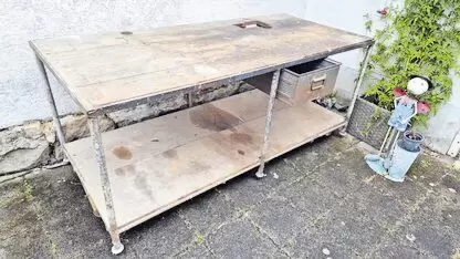 Alte Werkbank mit schwerem Metallgestell, 2 m x 0,90 m und einer  Metallschublade. Im hinteren Bereich ist ein Loch in der Holzp