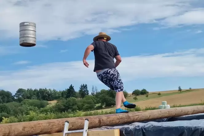 Auf dem Holzbalken stehend wird das Fass geworfen – dann fällt der Werfer ziemlich sicher in den Pool.