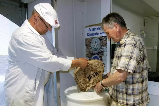 Stefan Gerhartsreiter (links) und Urban Roth beim Ausleeren ihrer Kronkorkensammlung in ein Fass im Färber Frischemarkt.