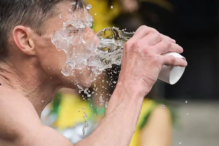 Ein Mann schüttet sich  Wasser ins Gesicht