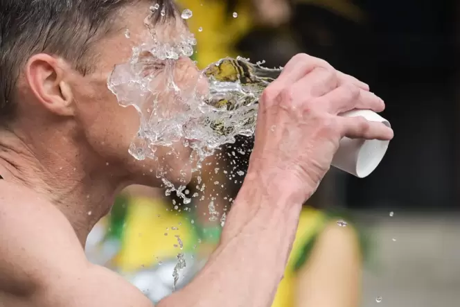 Ein Mann schüttet sich  Wasser ins Gesicht