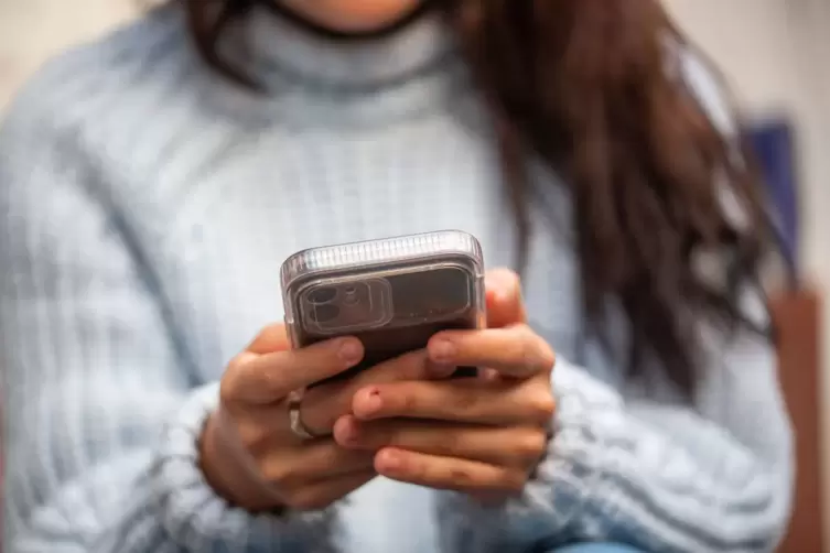Eine junge Frau hält ein Smartphone in den Händen