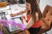 Eine Frau macht sich Notizen neben dem Laptop