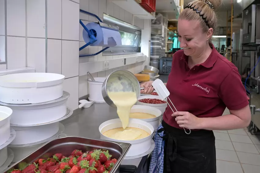 Rein damit: Die noch heiße Puddingmasse wird in die Form gefüllt und auf dem Biskuitboden verteilt.