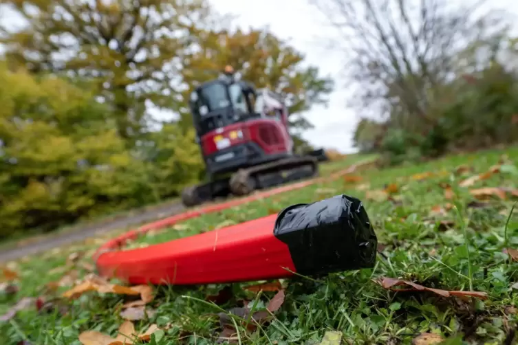 Ein Schutzrohr für Glasfaserkabel liegt vor einem Bagger