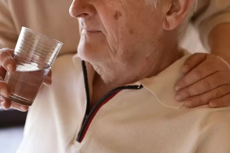 Eine Frau hilft einem Mann beim Trinken