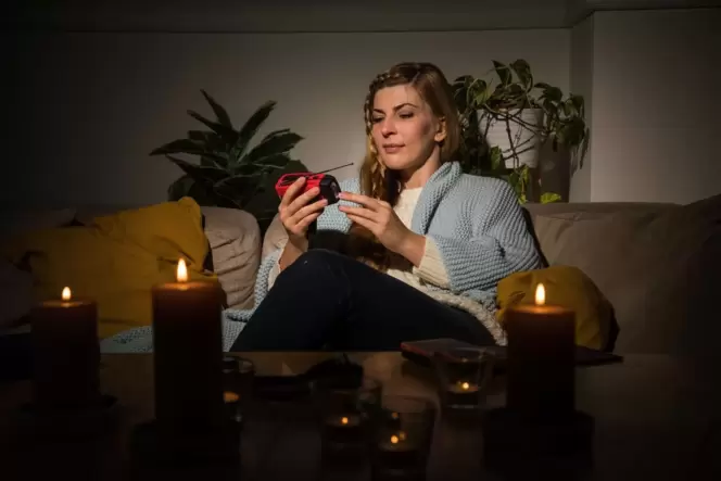 Eine Frau mit Kerzen während eines Stromausfalls auf dem Sofa