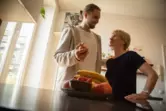 Ein junger Mann hilft einer älteren Frau in der Küche
