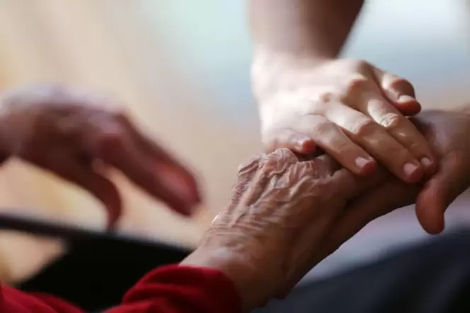 Eine Pflegekraft streicht einer Seniorin über die Hand