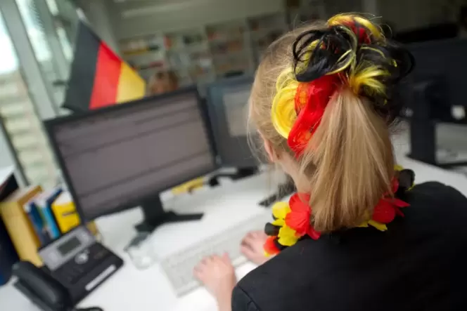 Eine Frau sitzt mit WM-Deko vor einem Computer