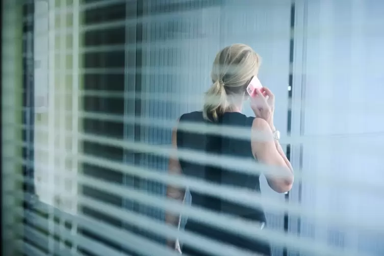 Eine Frau steht in einem B&uuml;rozimmer und telefoniert