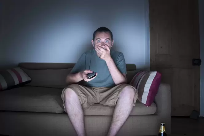 Gebannt auf dem Sofa vor dem Bildschirm: Was wie harmlose Unterhaltung wirkt, ist oft viel mehr Schaulust – das bequeme Zuschaue