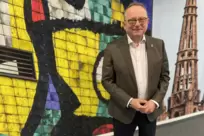 Klaus Blettner vor einer neuen Bildercollage im Foyer, das zu seinem Büro führt.