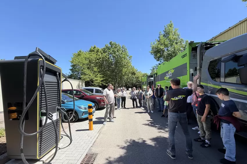 Eine Besuchergruppe bei einer Führung. Links befindet sich die 400-kW-Schnellladestation für die ersten E-Lkw.