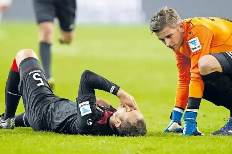 FCK-Torwart Julian Pollersbeck kniet neben verletztem Ewerton.
