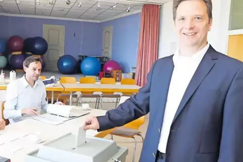 Der Wahlsieger Frank Rüttger bei der Stimmabgabe in Neuleiningen, links Wahlhelfer Dominik Freyland-Mahling.