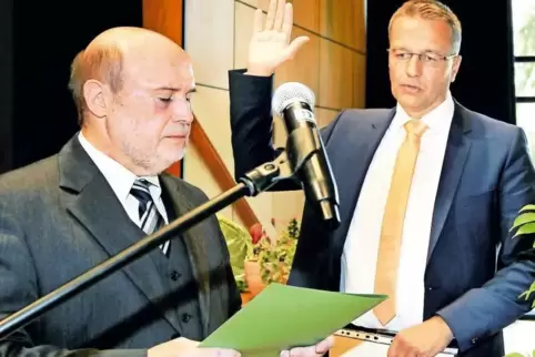 Der neue Neuhofener Ortsbürgermeister Ralf Marohn (rechts) legt im Bürgerhaus Neuer Hof den Amtseid ab. Sein Vorgänger Gerhard F