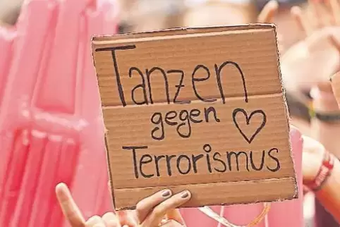 Festivalbesucher halten Schilder gegen Terrorismus hoch.