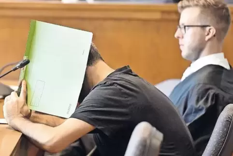 Mit einer Aktenmappe verbarg der Angeklagte zu Prozessbeginn sein Gesicht vor den Pressefotografen. Rechts sein Verteidiger Mari