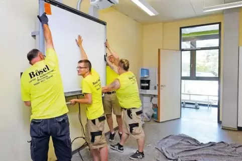 Neuer Standort: Umzugshelfer montieren eine Medientafel im Klassenraum in der Realschule plus in Dudenhofen.
