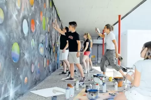 Auch das Weltall ist – im weitesten Sinn – unsere Heimat: Schüler des Nordpfalzgymnasiums beim Verschönern der Wand im Pausenhof