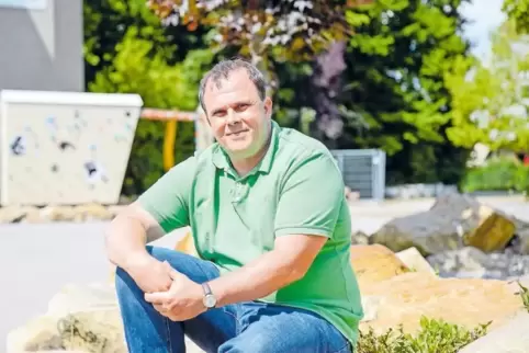 Ex-Schulleiter Andreas Bommer posiert vor dem naturnah gestalteten Schulhof statt vor der einstigen Betonwüste. Ermöglicht habe 