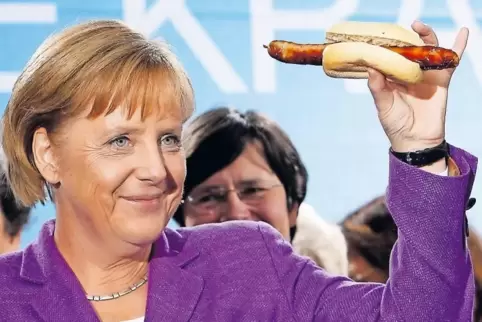 Bundeskanzlerin Angela Merkel 2009 in Thüringen mit Wahlkampf-Würstchen. SPD-Chef Martin Schulz isst im Norden Kieler Sprotten.