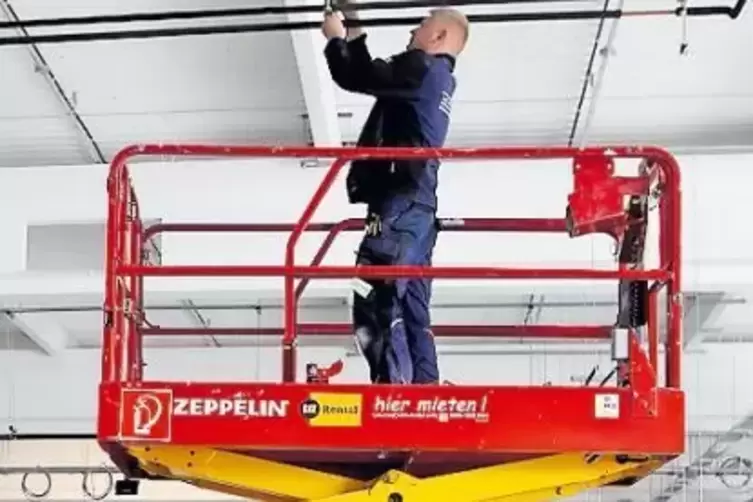 Ein Arbeiter verlegt Heizungsrohre unter der Decke.
